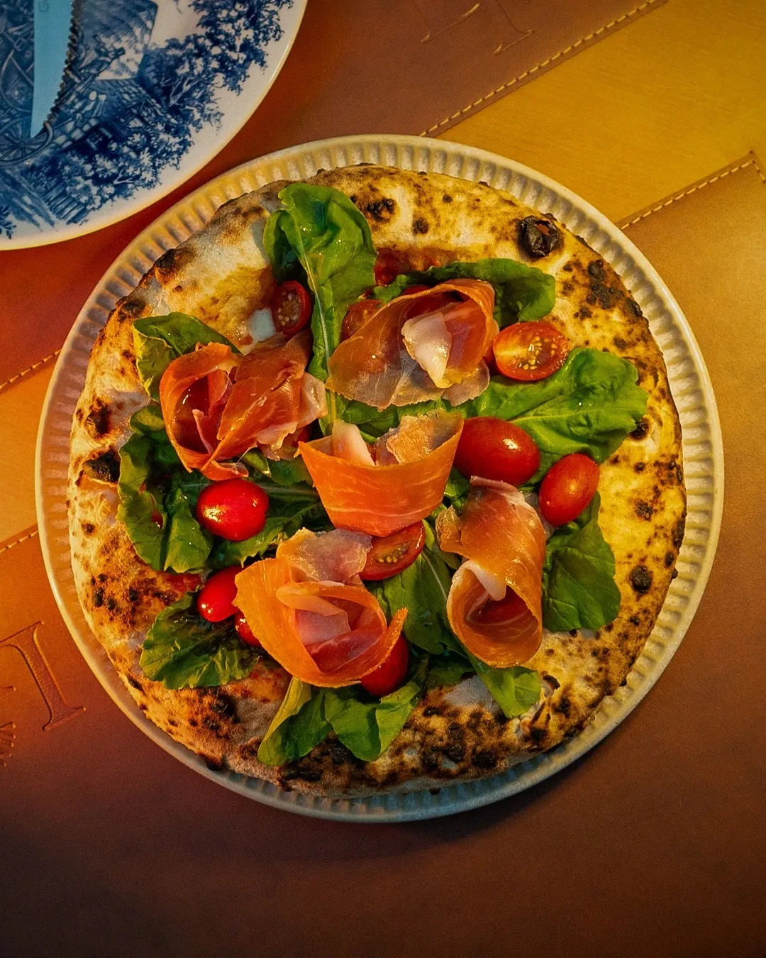 Pizza com prosciutto, taças e garrafa Primitivo sobre mesa de madeira